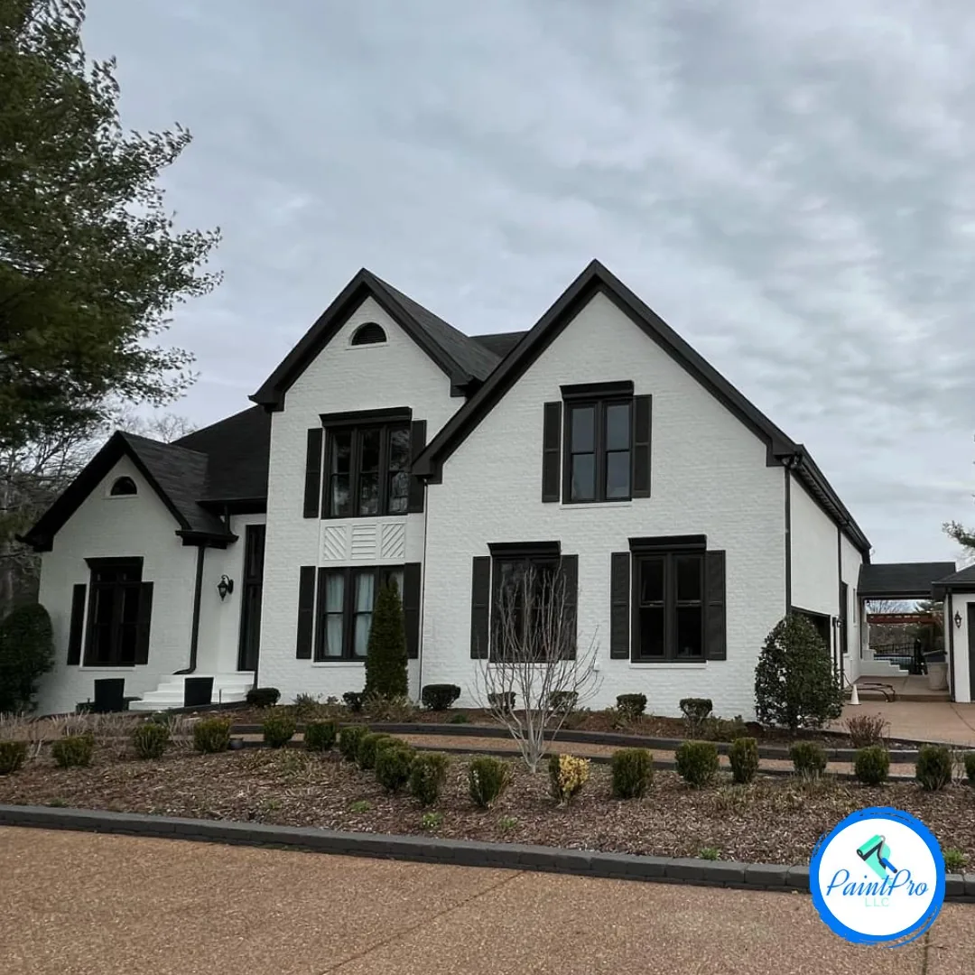 Large two-story home with white painted brick exterior and black shutters, trim, and roofline