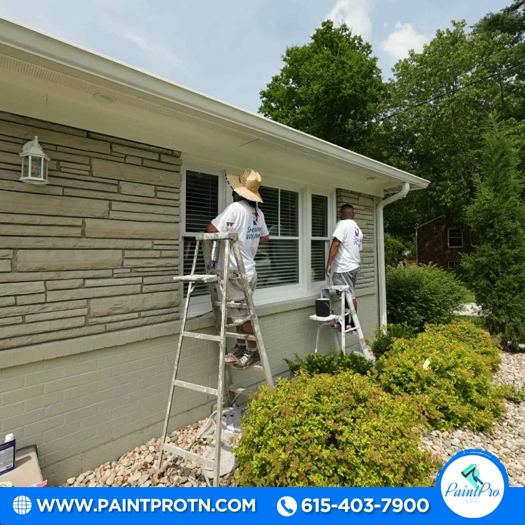 Painters on ladders applying exterior paint to a stone and siding home in Franklin, TN
